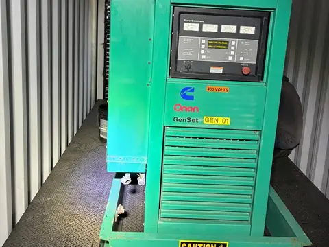 Green Cummins Onan genset inside its container with the PowerCommand control panel.